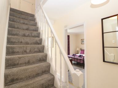 A carpeted staircase with white railing next to a bedroom with a metal bed frame at Pelham House Keswick