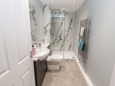 A bathroom with a sink, toilet, walk-in shower and towel rack at Pelham House in Keswick