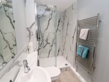 A bathroom with a sink toilet shower and towel rack at Pelham House in Keswick