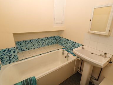 A bathroom with a bathtub and tiled wall next to a pedestal sink with a mirror cabinet Pelham House Keswick