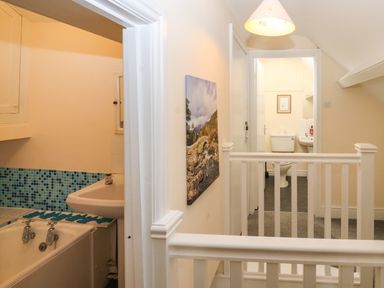 A bathroom with a bathtub and washbasin next to a hallway overlooking a toilet at Pelham House in Keswick