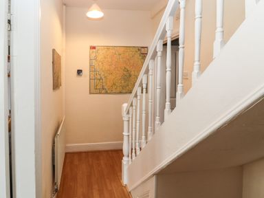 A hallway with wooden floor a white banister a map on the wall and a ceiling light at Pelham House in Keswick