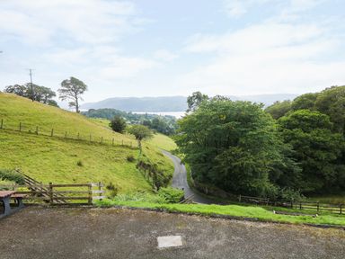 A rural landscape with a winding road trees and grassy hills at Low Skelgill in Troutbeck