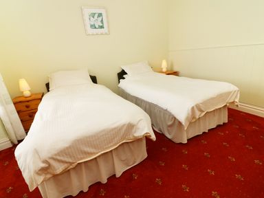 A bedroom with two single beds bedside tables with lamps and a framed picture on the wall at Low Skelgill in Troutbeck