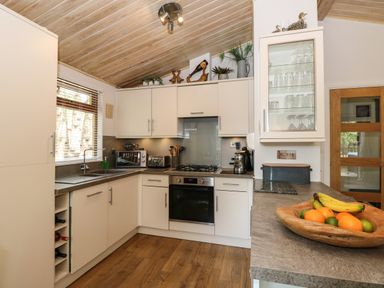 A kitchen with white cabinets a wooden ceiling and a fruit bowl on the counter at Footprints Lodge in Windermere