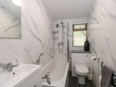 A bathroom with a bathtub sink toilet and a window at Footprints Lodge in Windermere