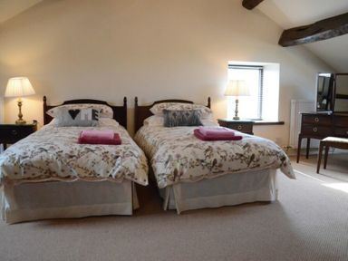 A bedroom with two single beds bedside tables lamps and a dressing table at Greety Gate House in Foxfield