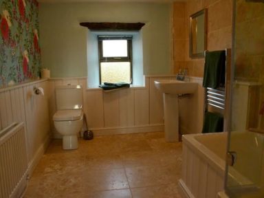 A bathroom with a toilet a sink a bathtub a window and floral wallpaper at Greety Gate House in Foxfield