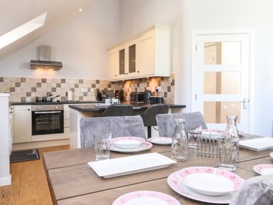 A dining table set with plates glasses and carafes in a kitchen with tiled backsplash and countertop at Sky View in Keswick