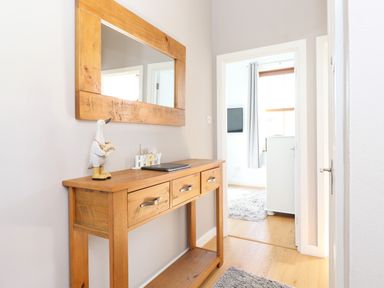A hallway with a wooden console table and mirror with a duck figurine and decorative words on the table at Sky View in Keswick