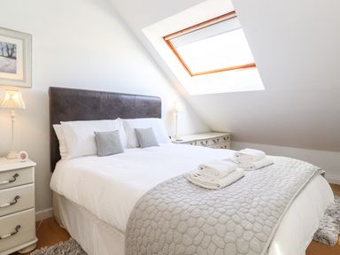 A bedroom with a bed cushions bedside tables lamps and a skylight window at Sky View in Keswick