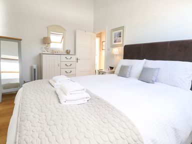A bedroom with a double bed and towels on a quilted bedspread a chest of drawers a standing mirror and a bedside table with a lamp at Sky View in Keswick