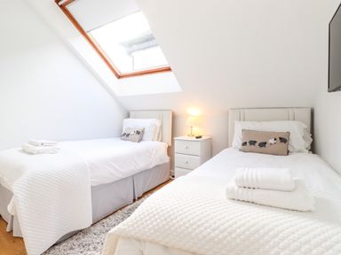 A bedroom with two single beds bedside table with lamp and folded towels on beds at Sky View in Keswick