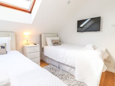A bedroom with two single beds a bedside table lamp and a wall mounted TV at Sky View in Keswick