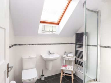 A bathroom with a toilet sink shower stool and small table under a skylight window at Sky View in Keswick