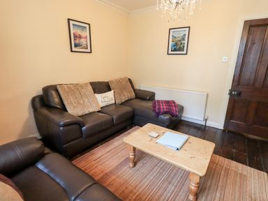 A living room with brown leather sofas a wooden coffee table and framed pictures on the wall at Walkers Rest in Windermere