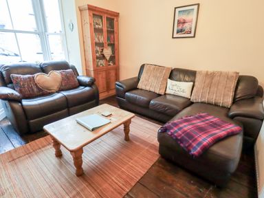 A living room with two leather sofas a wooden coffee table and a wooden cabinet at Walkers Rest in Windermere