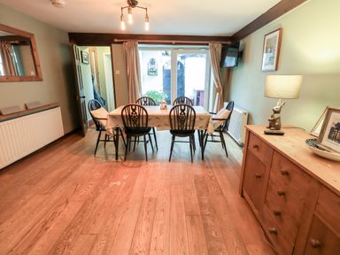 A dining room with six chairs around a table and a wooden cabinet with a lamp at Walkers Rest in Windermere