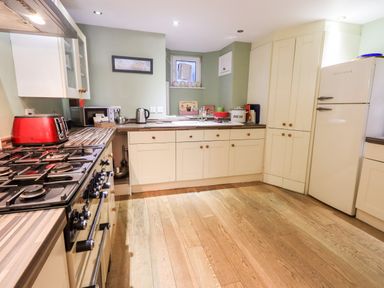 A kitchen with wooden floor cabinets a gas stove red toaster and a white refrigerator at Walkers Rest in Windermere