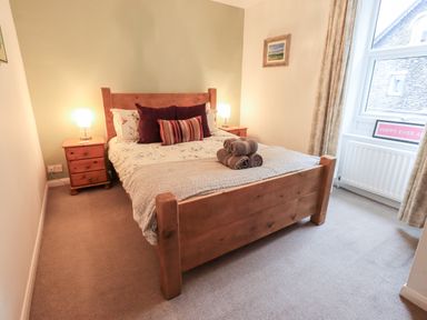 A bedroom with a wooden bed, bedside tables with lamps, and a window at Walkers Rest in Windermere