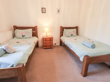 A bedroom with two single beds and a bedside table with a lamp at Walkers Rest in Windermere
