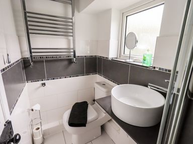 A bathroom with a toilet a round sink a window with soap and a mirror and a towel rail at Walkers Rest in Windermere