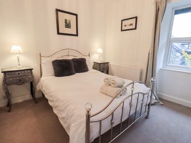 A bedroom with a metal bed frame two bedside tables with lamps and a window at Walkers Rest in Windermere