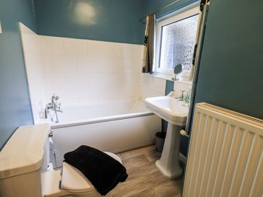 A bathroom with a bathtub toilet sink radiator and window at Walkers Rest in Windermere