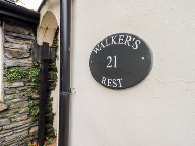 A black and white house number plaque on a wall next to a stone wall with some greenery at Walkers Rest in Windermere