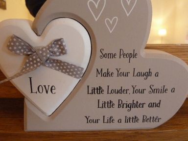 A heart-shaped wooden decoration with a bow and text about love on a wooden surface at Eribel Cottage in Threlkeld