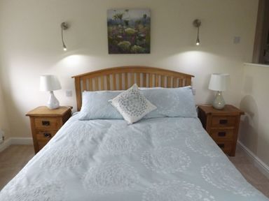 A bedroom with a wooden bed and bedside tables with lamps at Eribel Cottage in Threlkeld