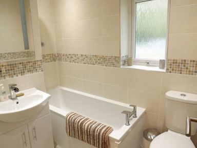 A bathroom with a bathtub a sink and a toilet at Eribel Cottage in Threlkeld
