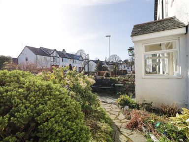 A garden with bushes and a stone path next to a white house at White House in Keswick