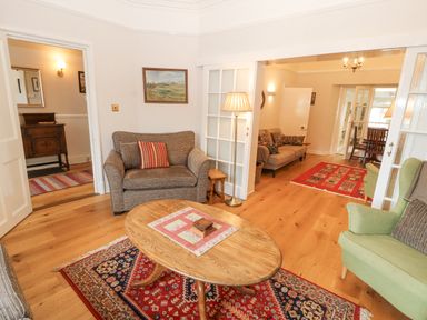 A sitting area with armchairs and a wooden coffee table on rugs with paintings on the walls at White House in Keswick