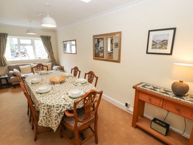 A dining room with a table set for six and a wooden sideboard with a lamp at White House in Keswick