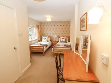 A bedroom with two single beds a wooden dressing table with mirror and a chair at White House in Keswick
