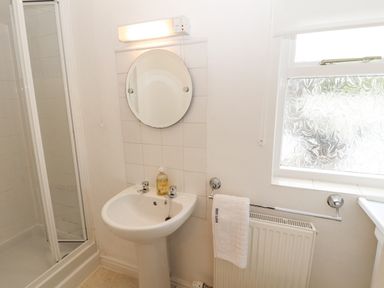 A bathroom with a white sink mirror towel radiator and a shower at White House in Keswick