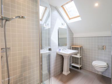 A bathroom with shower, sink, toilet, and mirror at Little Ellers in Portinscale near Keswick