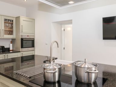 A kitchen with two stainless steel pots on a black countertop stove and built in oven in the background at Latrigg House in Keswick