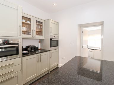 A kitchen with built in ovens cabinets with glass doors toaster and paper towel holder at Latrigg House in Keswick