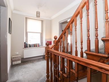 A stairway with wooden banisters and a window with books on the sill at Latrigg House in Keswick