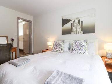 A bedroom with a double bed two bedside tables with lamps floral pillows and a wall art at Latrigg House in Keswick