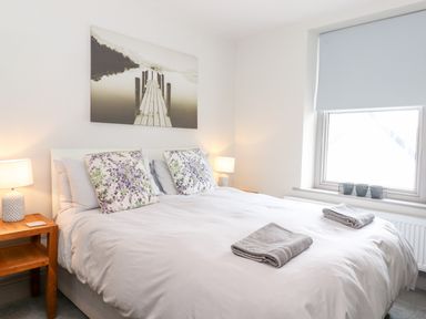 A bedroom with a double bed bedside tables lamps and a window at Latrigg House in Keswick