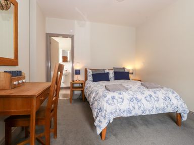 A bedroom with a double bed and two bedside tables with lamps and a wooden desk with a chair at Latrigg House Keswick