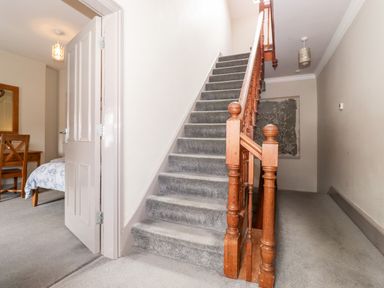 A stairway with wooden handrails and carpeted steps next to an open door leading to a bedroom at Latrigg House in Keswick