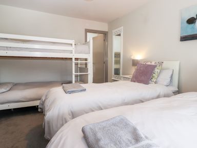 A bedroom with a bunk bed and two single beds with towels on them at Latrigg House in Keswick