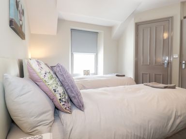A bedroom with two single beds white bedding and pillows next to a window with a closed blind at Latrigg House Keswick