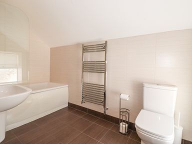 A bathroom with a bathtub sink toilet towel rack and toilet paper holder at Latrigg House in Keswick