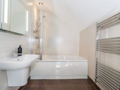 A bathroom with a sink a bathtub with a shower and a towel radiator at Latrigg House in Keswick