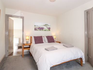 A bedroom with a double bed two bedside tables and an open door to a bathroom at Latrigg House in Keswick